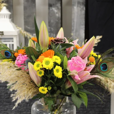 Bouquet ciré Pâques avec des lys des roses des chardons des germinis des plumes de paon des pampas