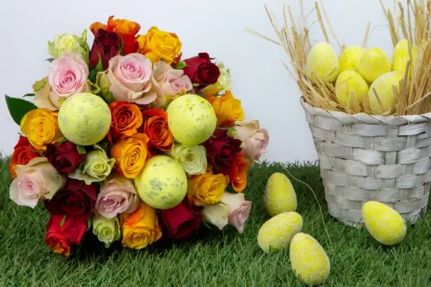 Tutti frutti Pâques : mélange de roses colorées sur du gazon avec un panier en osier blanc rempli d'œufs de pâques