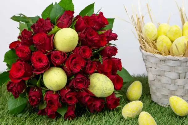 roses rouges de Pâques : roses rouges avec œufs de pâques en pic sur du gazon et un panier en osier blanc rempli d'œufs de pâques