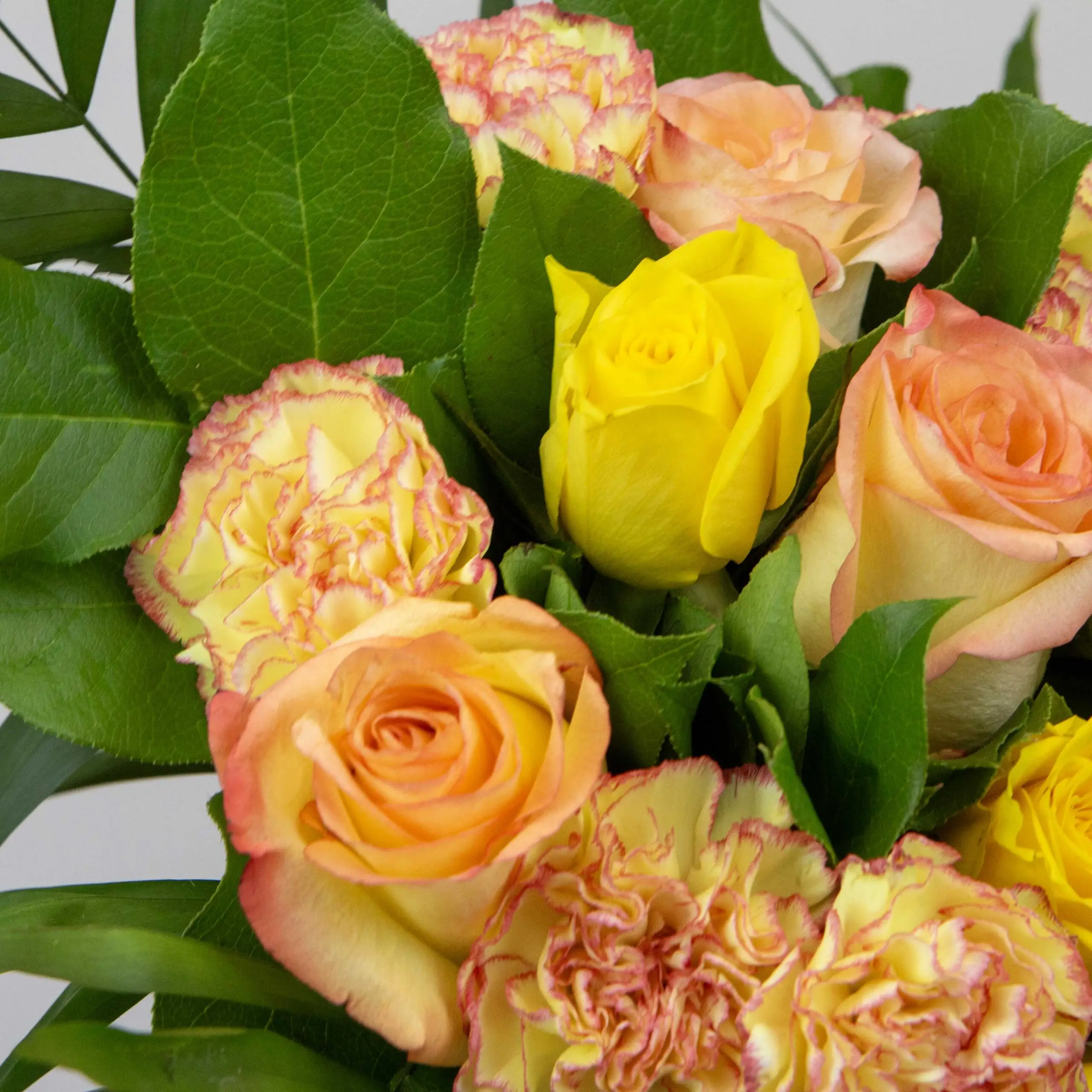 Bouquet Éclat de Soleil : roses oranges, roses jaunes, oeillets bicolore jaune/orangé, botte de sallal, chico