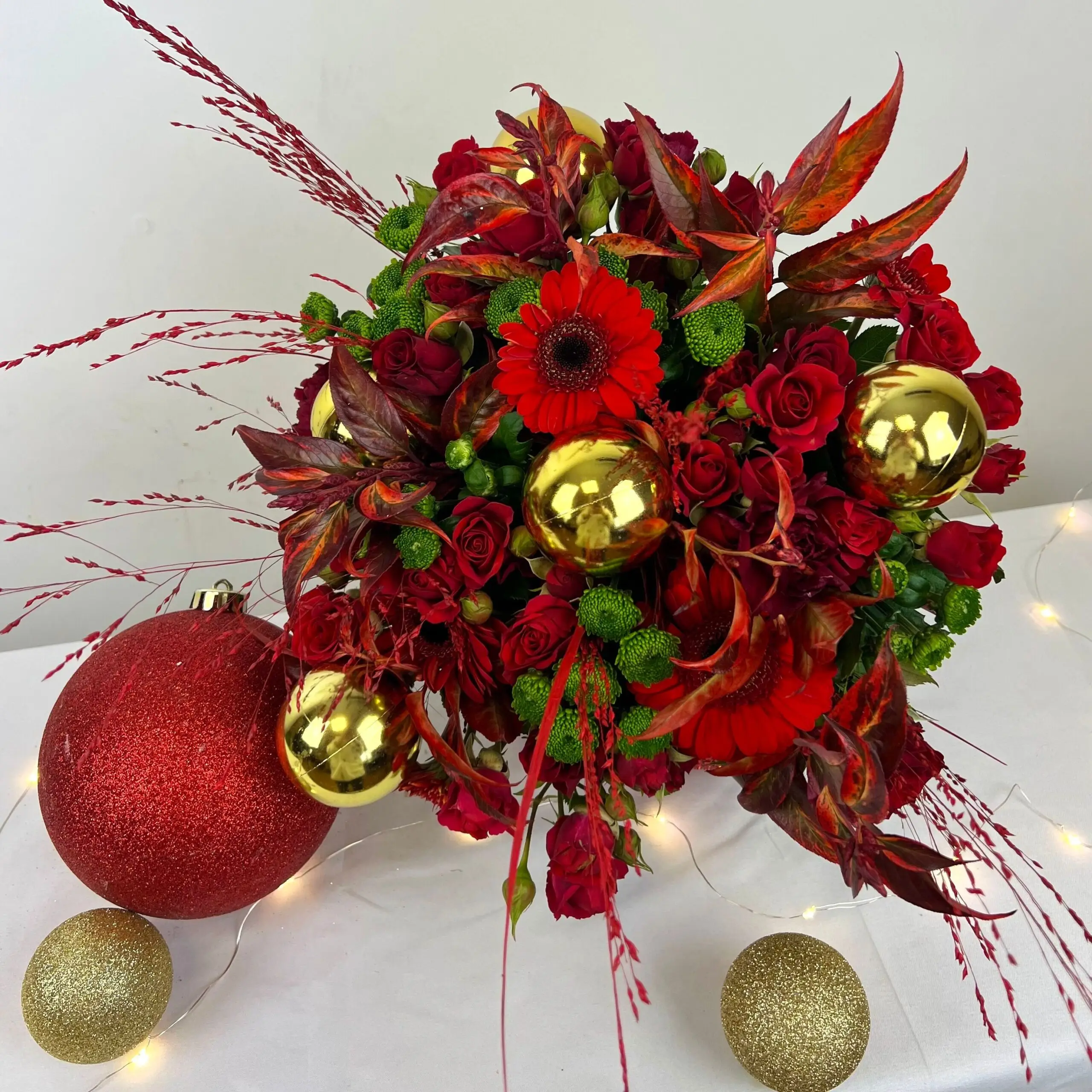 Bouquet de Noël 2024 aux couleurs chaleureuses rouges et dorés